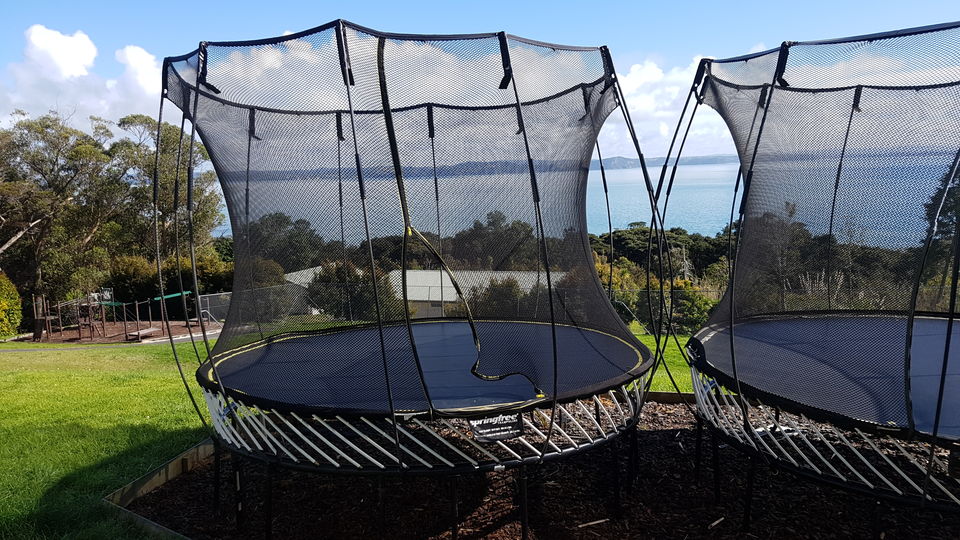 Two giant trampolines on the lawn above the water
