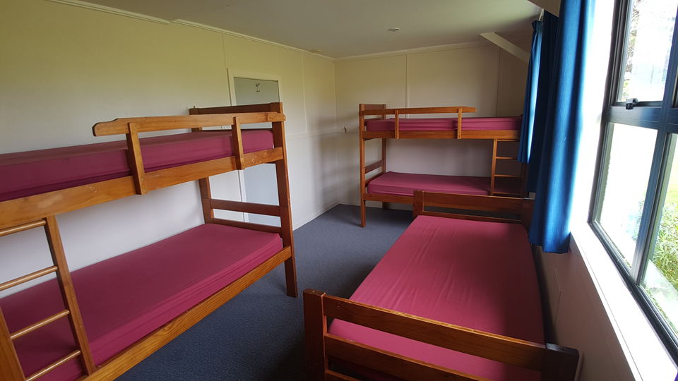 A dorm room with wooden bunks and foam mattresses